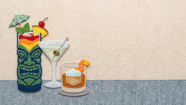 A handcrafted cut felt illustration of mixed drinks, including a tiki glass, martini, and whiskey, set against a minimalist grey and beige background with ample copy space.