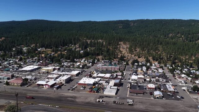 Aerial of small town center and forest edge in Cle Elum Washington with commercial buildings and residential areas in summer