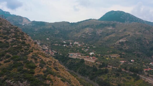 Cinematic aerial drone wide shot of Mesudiye village in Dat&ccedil;a, Mugla, featuring the unique nature, winding roads, and lush green valley nestled between mountains.