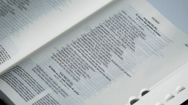 Detailed view of a male hand pointing with his index finger to the lines of a psalm of a holy bible in spanish
