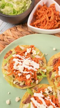 Mexican tostadas with beans, lettuce, chicken, and fresh cheese