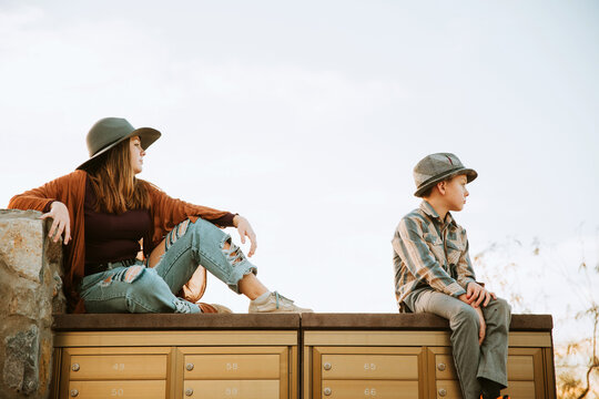 Siblings sitting on top of neighborhood mailboxes
