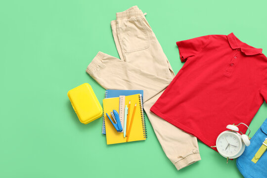 Flat lay of childrens school supplies and clothing on green background