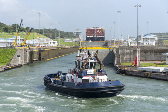 Harbor tug supporting vessel transit inside the Agua Clara Locks. Modern canal facilities and navigation infrastructure.