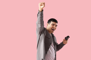 Happy young man with game pad on pink background © Pixel-Shot