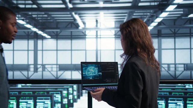 Software developers manage AI technology in a server farm with laptop, combining AI operations, document review and infrastructure review within a controlled technical environment.