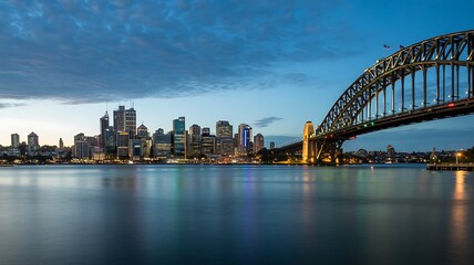 Naklejka premium Sydney harbour bridge with city skyline reflected on calm waterfront at dusk
