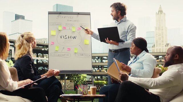 Businessman presenting ideas on whiteboard during informal discussion, smiling and pointing to sticky notes for action plan implementation, reviewing strategy.