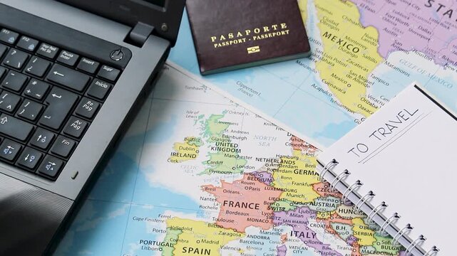 Detailed view of a planning travel concept with a notebook a passport and a laptop over europe and north america maps at background