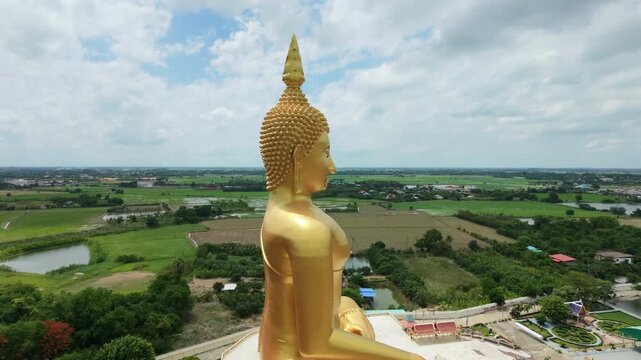 Panoramic aerial view of Thailand's largest Buddha statue, surrounded by rice paddies, in Pathum Thani Province.