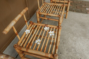 Wooden table and chair and frangipani flowers in restaurant, outdoor cafe scandinavian style,Rattan detailed craftsmanship and pattern,summer beach concept. © wanatithan