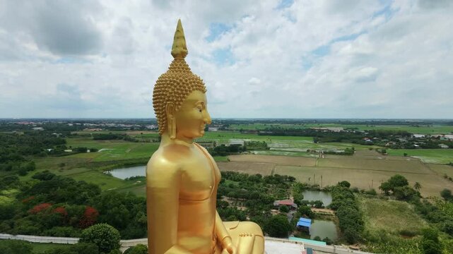 Panoramic aerial view of Thailand's largest Buddha statue, surrounded by rice paddies, in Pathum Thani Province.
