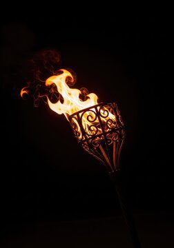 Vibrant fire dances inside an ornate wrought iron torch, illuminating the surrounding darkness with a warm, flickering light and heat, sconce, energy, cozy