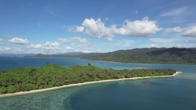 An isolated, uninhabited tropical island with a beach of crystal clear waters and white sand seen from afar. Palm trees and untouchable local flora. Filmed with a Drone in Palawan, Philippines, Asia.