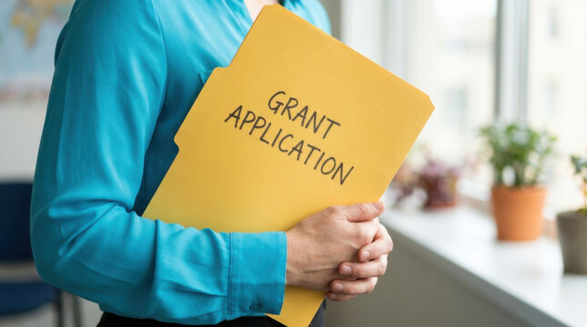 Grant application folder in hands at office window, funding approval concept with close up torso and blurred indoor background