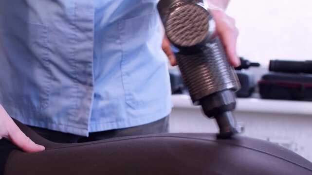 Muscle tension relief. Recovery massage. Unrecognizable male hands professional expert using physiotherapy gun for patient back.