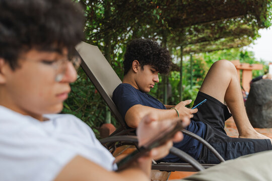 Teen boys using cell phones outdoors relaxing social networking