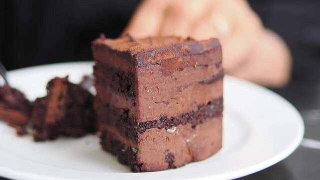 Person enjoying a slice of chocolate cake