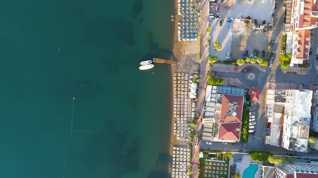 Marmaris, Turkey. Strict top-down aerial view of geometric beach umbrellas and sunbeds lining the promenade, first-line hotels and calm turquoise sea in morning light. Aerial View, HEAD OVER SHOT