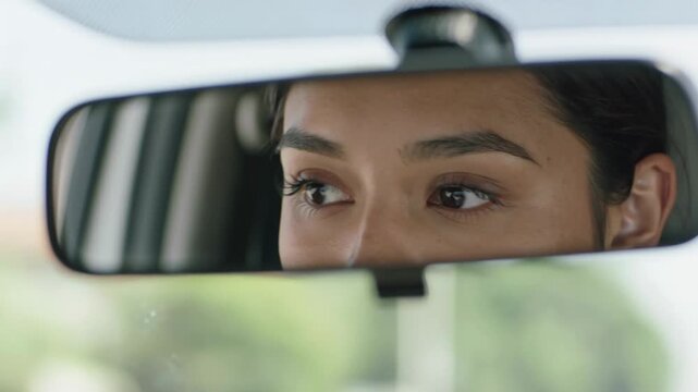 Close-up of woman's eyes reflected in car rearview mirror