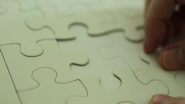 Horizontal 4K footage of hands repeatedly testing blank white puzzle pieces until finding the correct piece that fits perfectly