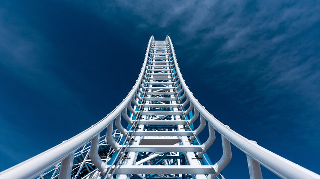 Steel roller coaster tracks rising high into deep blue sky.