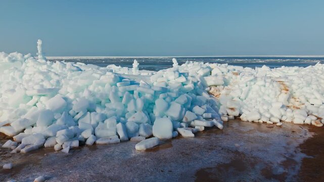 Drone flies sideways beside towering Baltic Sea ice ridges on Tuja Beach coast