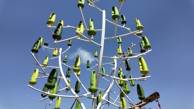 Slow motion video of a modern tree-shaped art installation featuring stylized plastic leaf elements at Futuroscope in Poitiers, France.