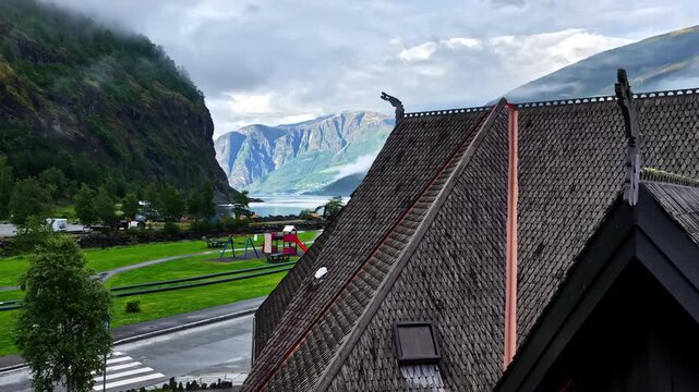 Fjord landscape revealed above rooftops with mountains in Aurland Norway, drone ascend pullback