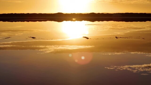 Low aerial shot across a salt pond revealing a rising sun. Walvis Bay, Namibia