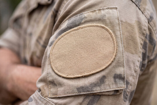 Blank beige velcro patch on sleeve of camouflage military uniform