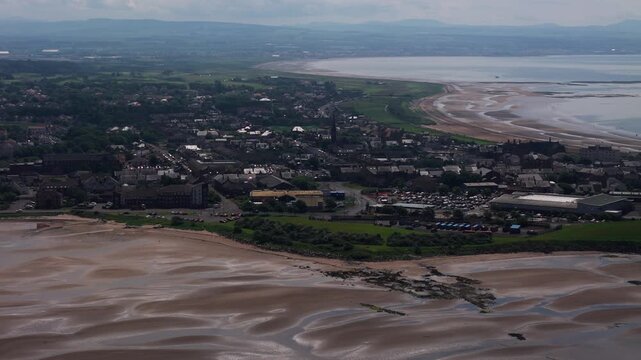 Troon, South Ayrshire, Scotland, at dawn, showing the sandy beach, coastal town, shoreline and calm morning light along the Firth of Clyde, cinematic aerial panning view