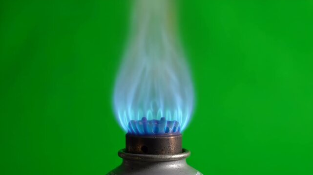 Blue gas flame igniting and burning steadily on a bright green screen background for compositing