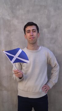 Vertical shot of a person waving Scottish flag in slow motion. Scotland country flag.