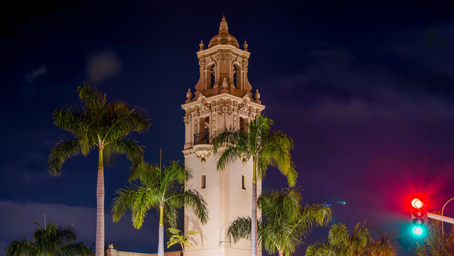 Historic Bell Tower Illuminated at Night with Palm Trees and Traffic Light