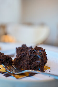 Chocolate crumbs and cake fork on dish during eating cake in coffee shop.