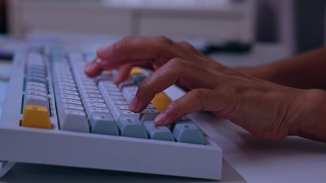 Hands typing on colorful mechanical keyboard at office desk closeup, computer key input for work, study, writing, data entry, communication, technology workstation