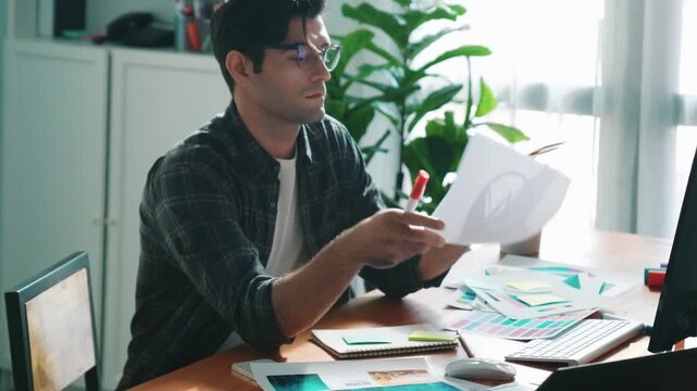 Professional designer writing and designing logo graphic at meeting. Closeup of business man working on colored palettes and writing idea on sticky notes on table with equipment and paper. Symposium.