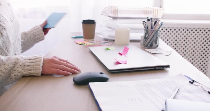 Mental work. Office routine. Unrecognizable female freelancer at desk writing task in notebook with sticky notes on laptop indoor.