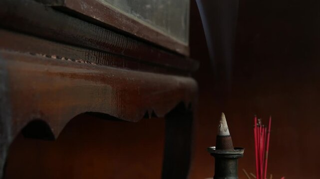 Incense Cone Burning with Smoke and Red Joss Sticks on Shrine, Buddhist Ritual Close-Up