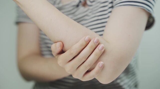Close up of a woman holding her painful elbow, illustrating elbow pain, tendon inflammation, muscle strain, joint injury, physical therapy, rehabilitation, healthcare, recovery, and wellness.