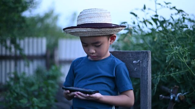 4 Year Old ASEAN Boy Using Tablet in Vegetable Garden Exploring Smart Farming AI Technology and Future Food Security Concept