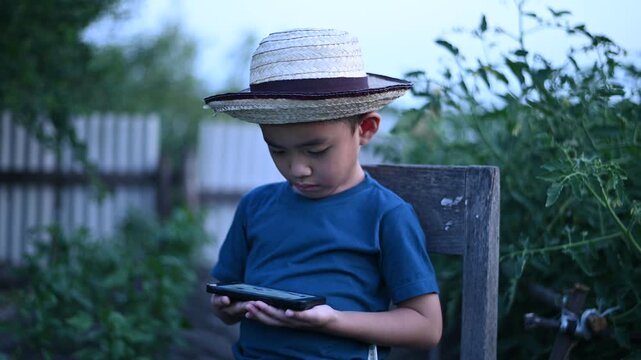 4 Year Old ASEAN Boy Using Tablet in Vegetable Garden Exploring Smart Farming AI Technology and Future Food Security Concept