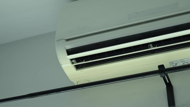 Horizontal 4K video showing smooth continuous automatic swinging movement of an air conditioner louver flap circulating cool air in room