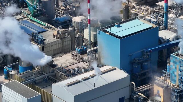 High angle view of a large pulp mill processing eucalyptus for cellulose production. White smoke rises from smokestacks in the complex