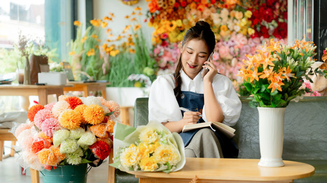 Owner business flower shop taking note order from customer by phone