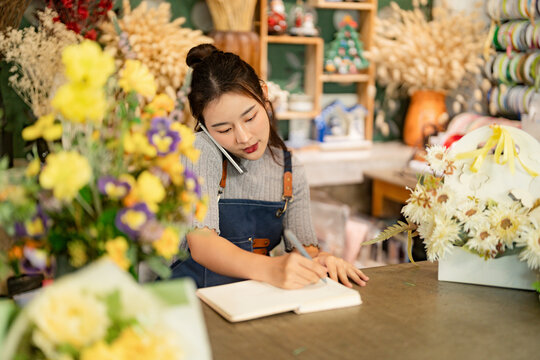 Owner business flower shop taking note order from customer by phone