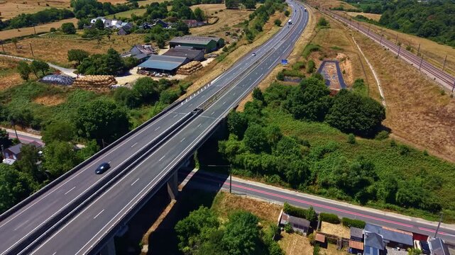 L'Armoricaine D31 crosses the Mayenne River corridor beside the Paris Brest railway in Change, Mayenne, Pays de la Loire, France, surrounded by farmland and transport infrastructure, drone pullback.