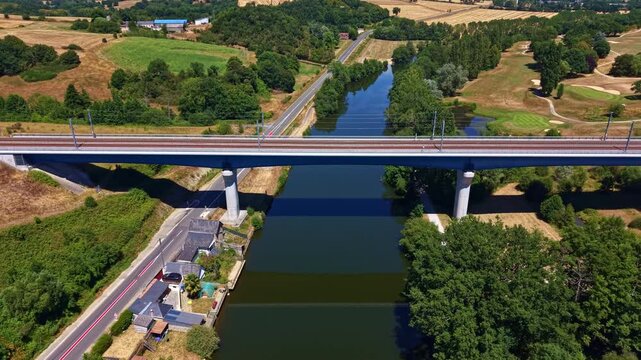 L&rsquo;Armoricaine D31 and the Paris Brest railway cross the Mayenne River in Change, Mayenne, Pays de la Loire, France, linking major transport corridors through a rural landscape, drone forward flyover