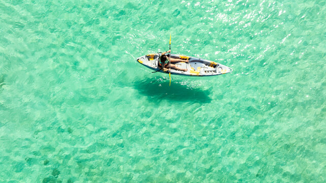 Aerial view of a woman and a young man kayaking on clear blue waters at Andaman Island. She does water sports activities